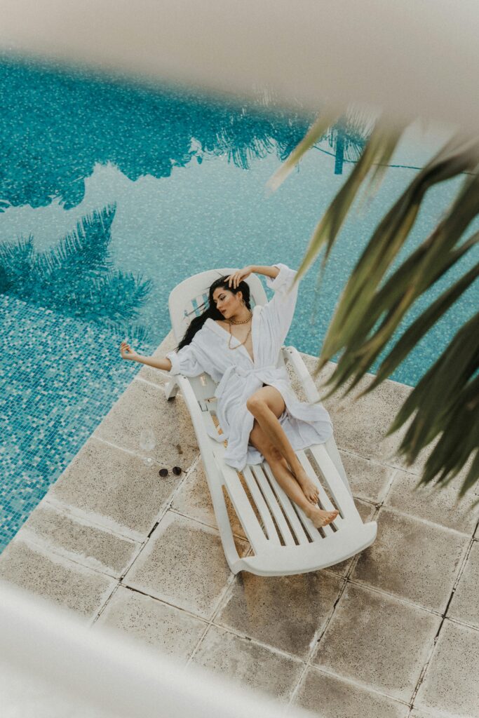 Woman in a bathrobe lounging by a serene poolside, enjoying a relaxing moment. Luxury Mediterranean Wellness