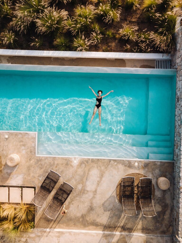 Stunning aerial shot of a woman relaxing in a luxurious infinity pool at a villa in Naxos, Greece.