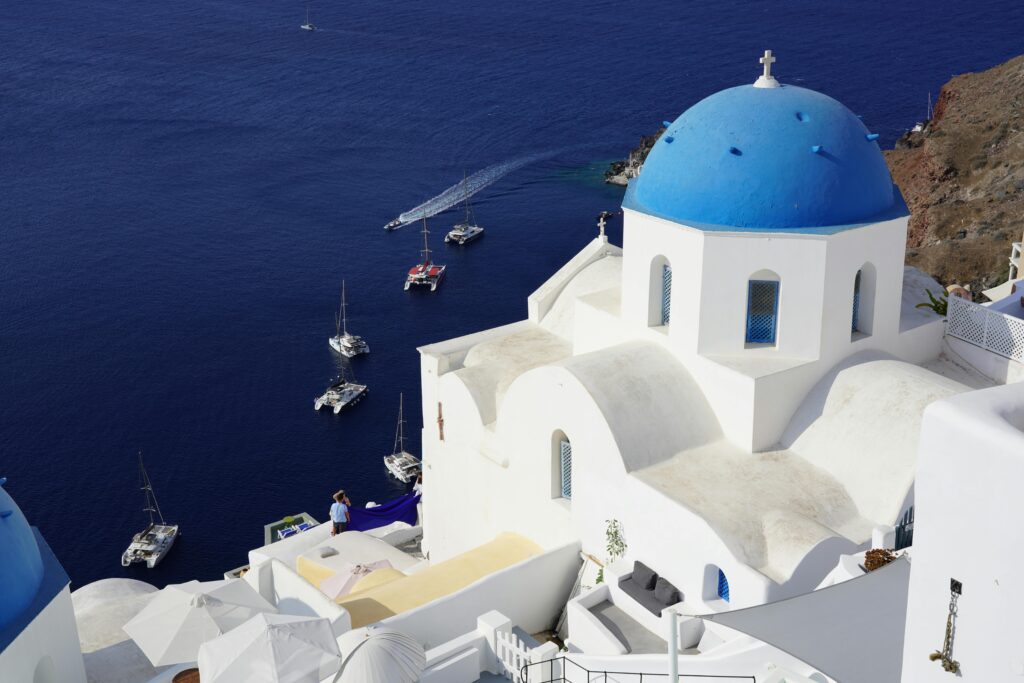 Scenic view of Santorini's blue-domed church with the Aegean Sea backdrop.